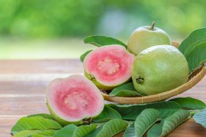 Red Guava fruit with leaf on blur garden background, Fresh Pink Guava fruit on wooden basket over natural farm background.